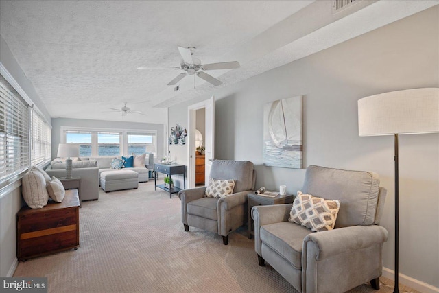 living room with a textured ceiling, ceiling fan, carpet flooring, visible vents, and baseboards