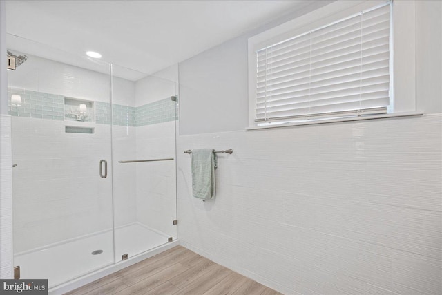 full bath with a shower stall, tile walls, and wood finished floors