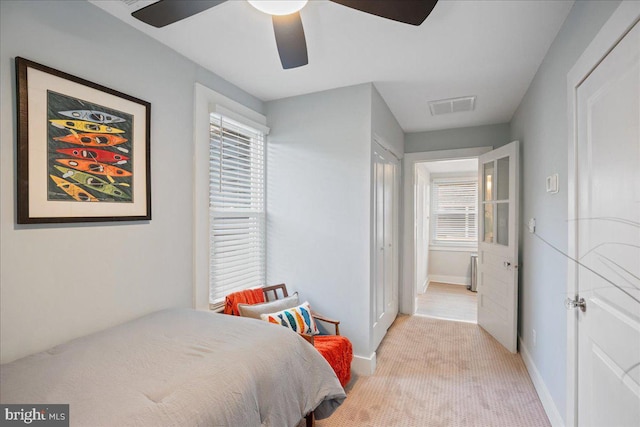 bedroom featuring a ceiling fan, light colored carpet, visible vents, and baseboards