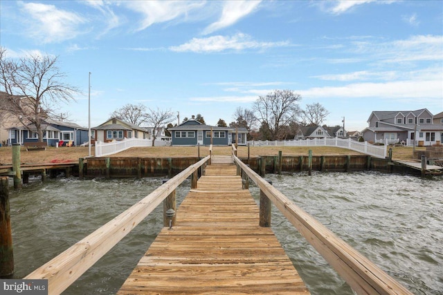 view of dock featuring a water view, a residential view, and fence