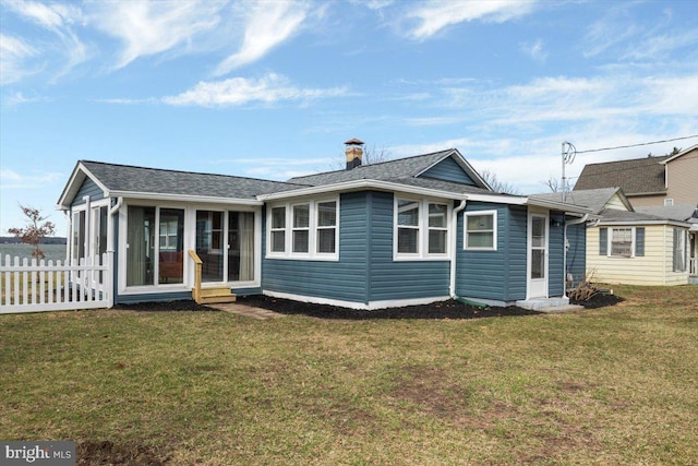 view of front of house featuring a shingled roof, a front yard, a sunroom, and fence