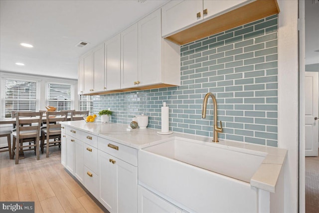 kitchen with light countertops, a sink, white cabinetry, and decorative backsplash