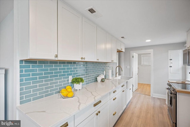 kitchen with electric stove, light wood-type flooring, visible vents, and white cabinets