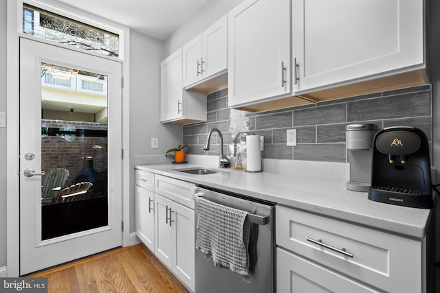 kitchen featuring a sink, white cabinetry, light wood-style floors, decorative backsplash, and dishwasher