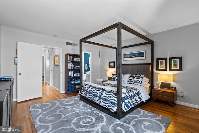 bedroom featuring wood finished floors, visible vents, and baseboards