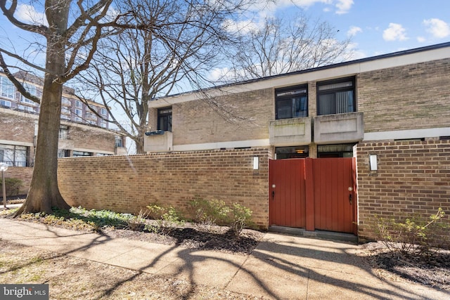 exterior space featuring brick siding and fence