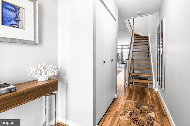 hallway with stairs, baseboards, and light wood-style floors