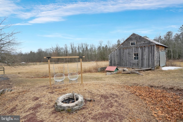 view of yard with an outdoor fire pit, a rural view, and an outdoor structure