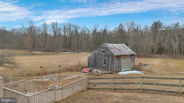 exterior space featuring a storage unit, a rural view, fence, and an outdoor structure