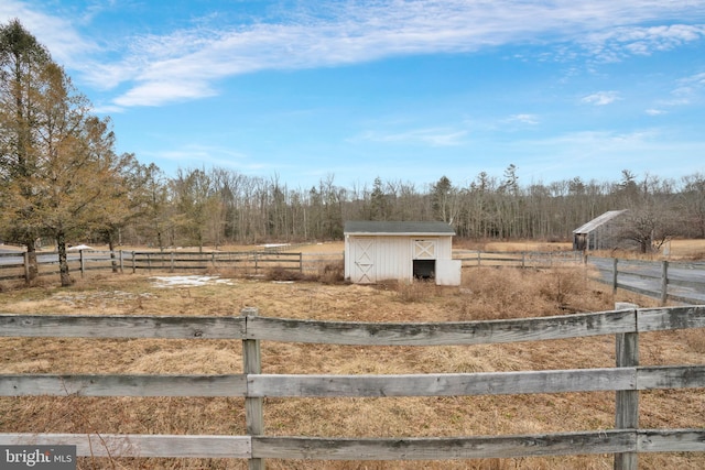 view of yard with fence, an outbuilding, and a rural view