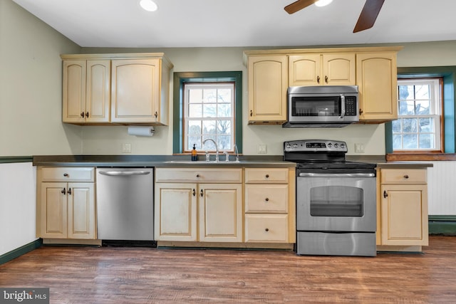 kitchen featuring dark countertops, a wealth of natural light, appliances with stainless steel finishes, and a sink