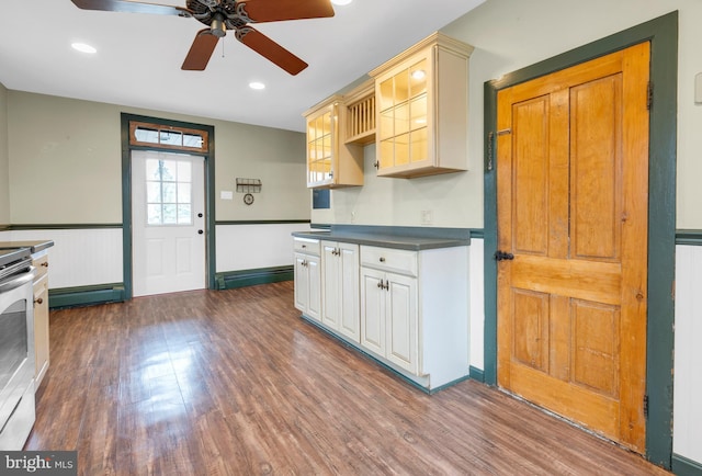 kitchen featuring dark wood-style floors, dark countertops, glass insert cabinets, a baseboard heating unit, and stainless steel range with electric cooktop