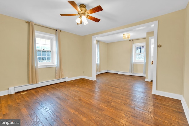 empty room with plenty of natural light, baseboard heating, and dark wood-style flooring