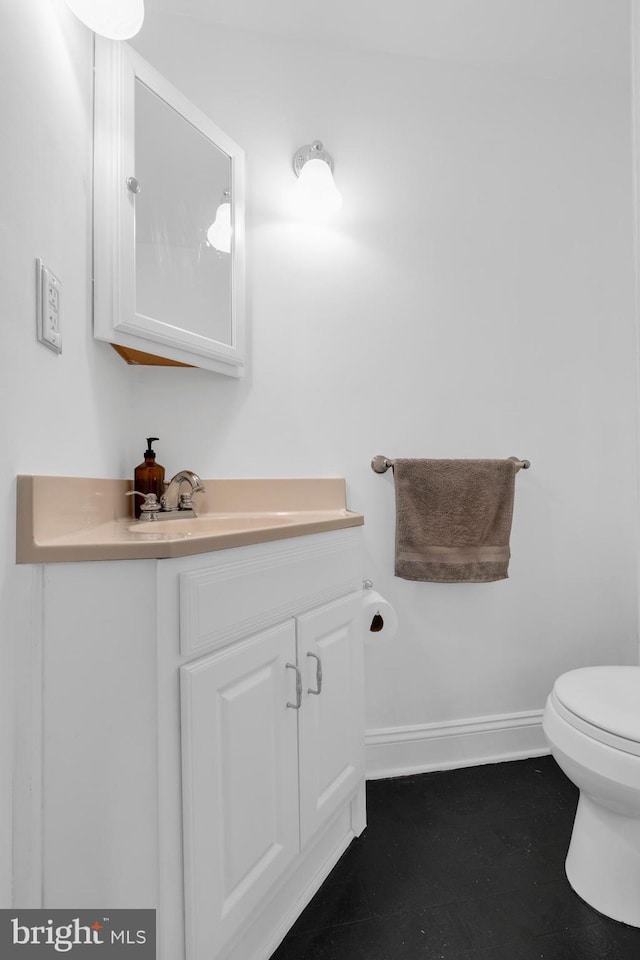 half bathroom featuring toilet, vanity, and baseboards