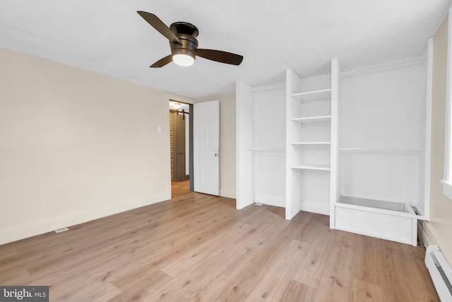 unfurnished bedroom featuring a baseboard heating unit, ceiling fan, light wood finished floors, and baseboards