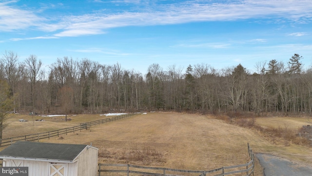 view of yard with fence, an outbuilding, and a rural view