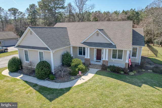 view of front of house with a front yard, roof with shingles, and fence