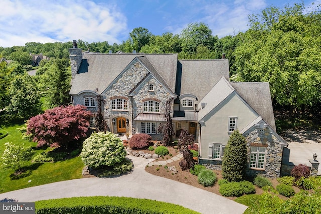 french country inspired facade with a chimney and stucco siding