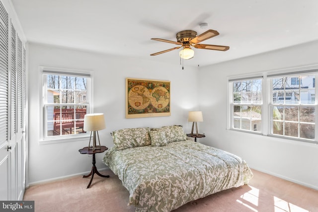 carpeted bedroom with ceiling fan, multiple windows, a closet, and baseboards