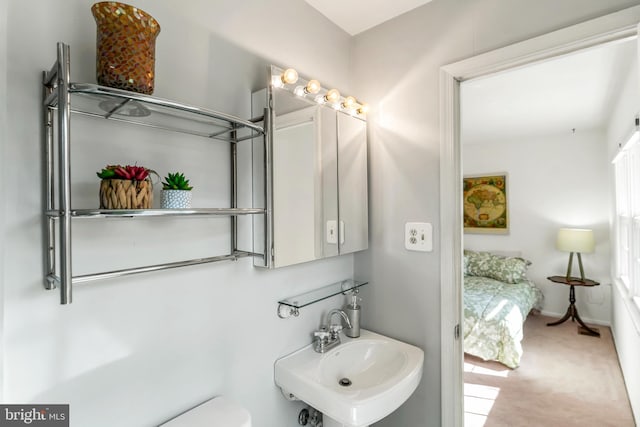 half bathroom featuring baseboards, a sink, and toilet