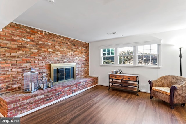 living area with visible vents, a fireplace, baseboards, and wood finished floors