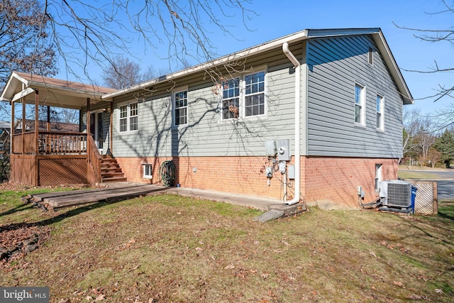 rear view of property featuring a lawn, a deck, and cooling unit