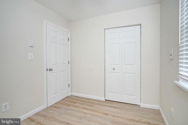 unfurnished bedroom with light wood-type flooring, baseboards, and a closet