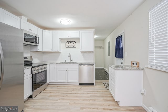 kitchen featuring appliances with stainless steel finishes, a baseboard radiator, white cabinetry, and a sink