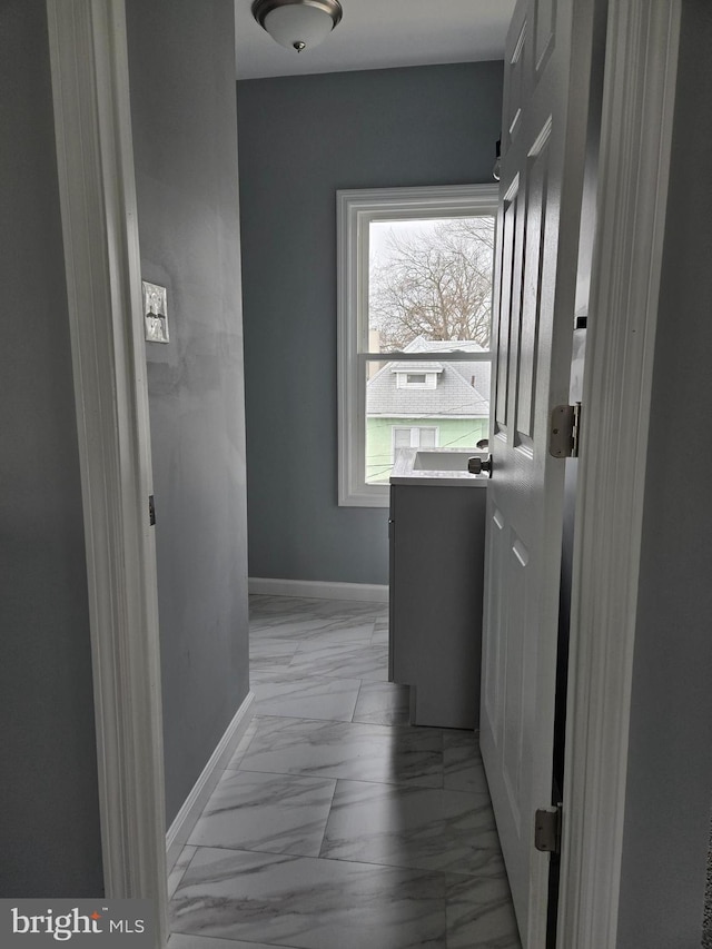 corridor with marble finish floor and baseboards