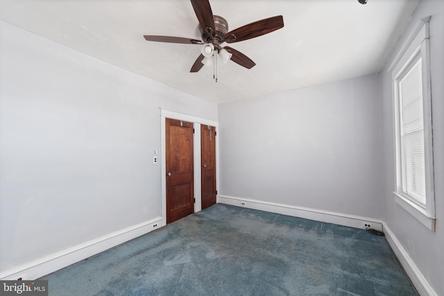 unfurnished room with dark colored carpet, baseboards, a healthy amount of sunlight, and ceiling fan