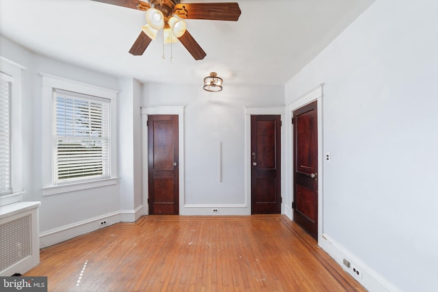 unfurnished bedroom featuring radiator heating unit, baseboards, and light wood-type flooring