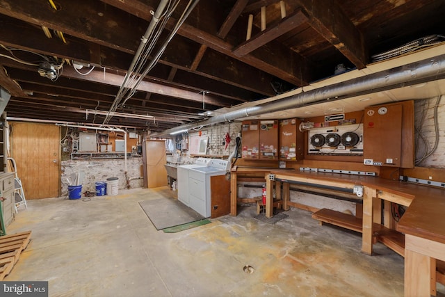 unfinished below grade area featuring a workshop area, electric panel, and separate washer and dryer