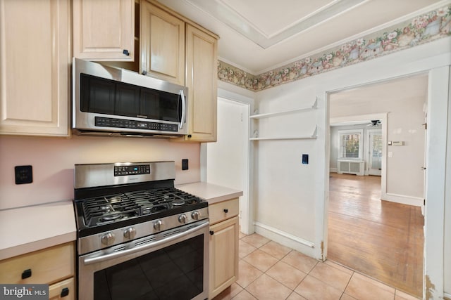 kitchen with crown molding, light brown cabinetry, light countertops, appliances with stainless steel finishes, and light tile patterned flooring