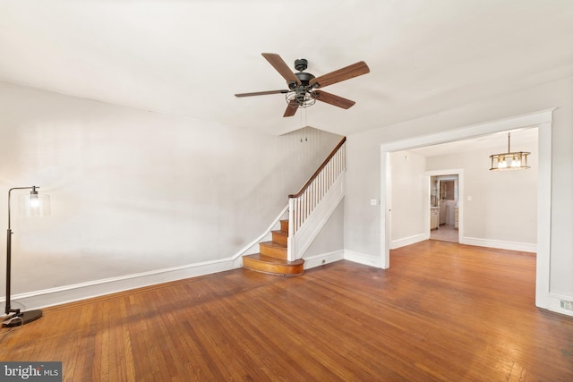 unfurnished living room with baseboards, hardwood / wood-style floors, and stairs