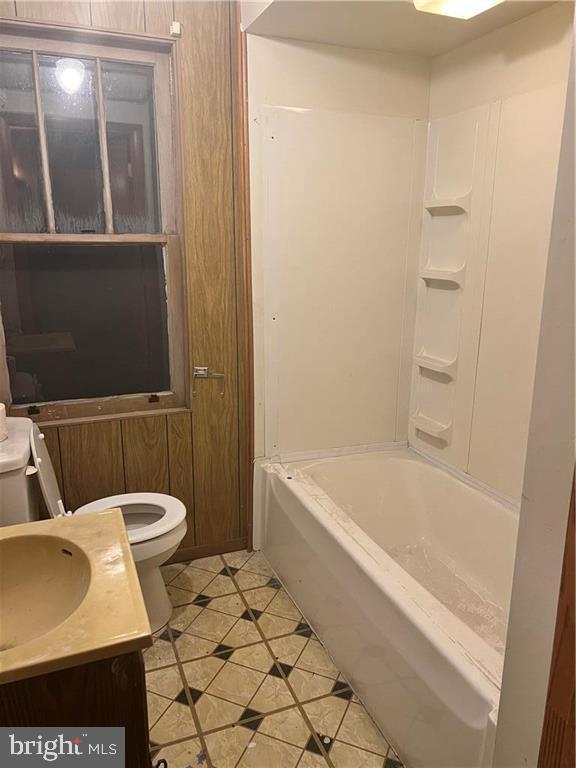 bathroom with washtub / shower combination, vanity, toilet, and tile patterned floors