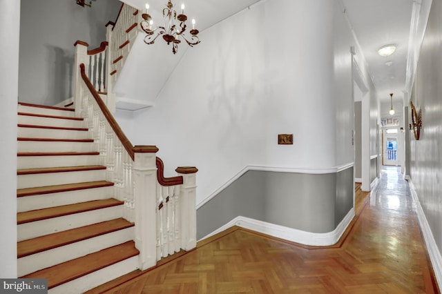 stairway featuring a chandelier and baseboards