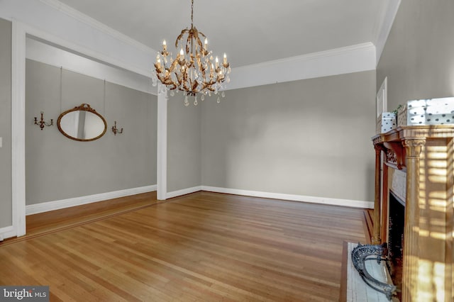 unfurnished living room with baseboards, ornamental molding, a chandelier, and wood finished floors