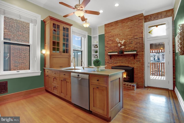 kitchen with dishwasher, light countertops, a sink, and light wood-style flooring