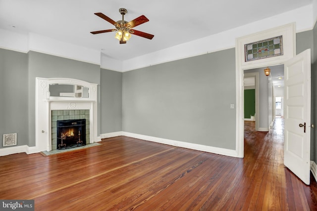 unfurnished living room with visible vents, baseboards, a tiled fireplace, ceiling fan, and dark wood-style flooring