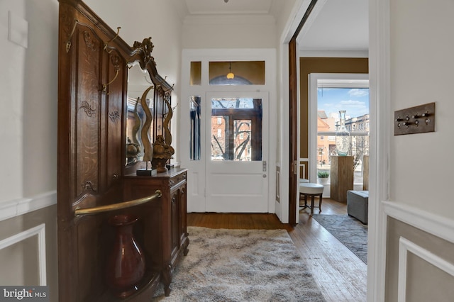 entryway with ornamental molding and wood finished floors