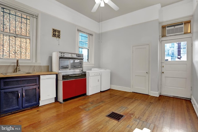 kitchen featuring visible vents, a wall unit AC, white dishwasher, light countertops, and a sink