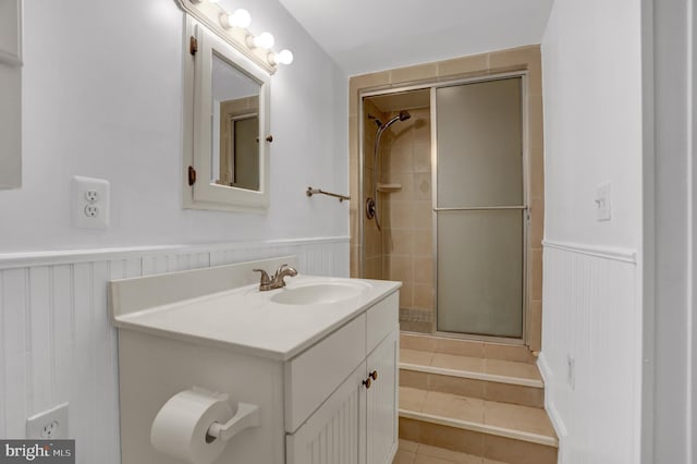 bathroom featuring vanity, a tile shower, and wainscoting