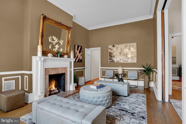 living room with baseboards, hardwood / wood-style floors, a tiled fireplace, and crown molding