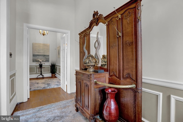 corridor featuring light wood-style floors and a notable chandelier