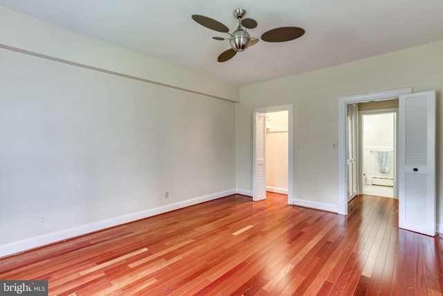 unfurnished bedroom with baseboards, wood-type flooring, ceiling fan, a baseboard heating unit, and a closet