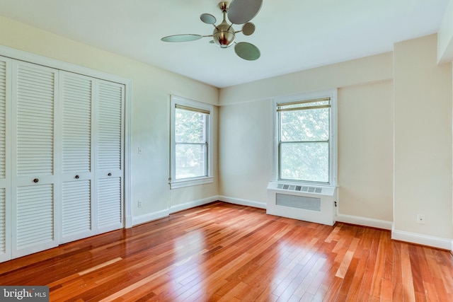 unfurnished bedroom featuring light wood finished floors, multiple windows, a closet, and baseboards