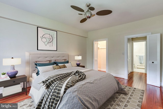 bedroom featuring a baseboard heating unit, baseboards, hardwood / wood-style floors, and a ceiling fan