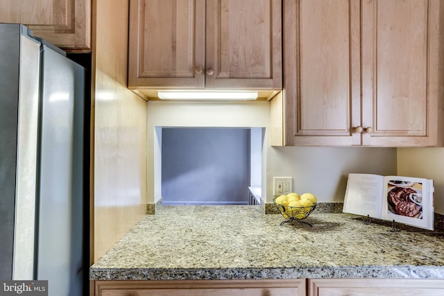 kitchen featuring light stone counters and freestanding refrigerator