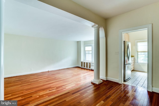 spare room with baseboards, decorative columns, and hardwood / wood-style floors