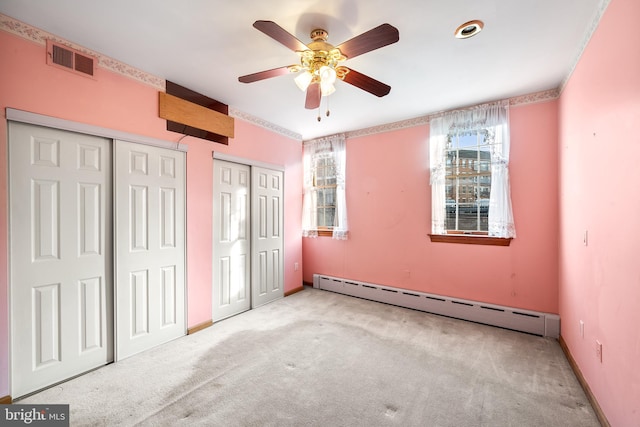 unfurnished bedroom with light carpet, baseboards, visible vents, a baseboard heating unit, and multiple closets